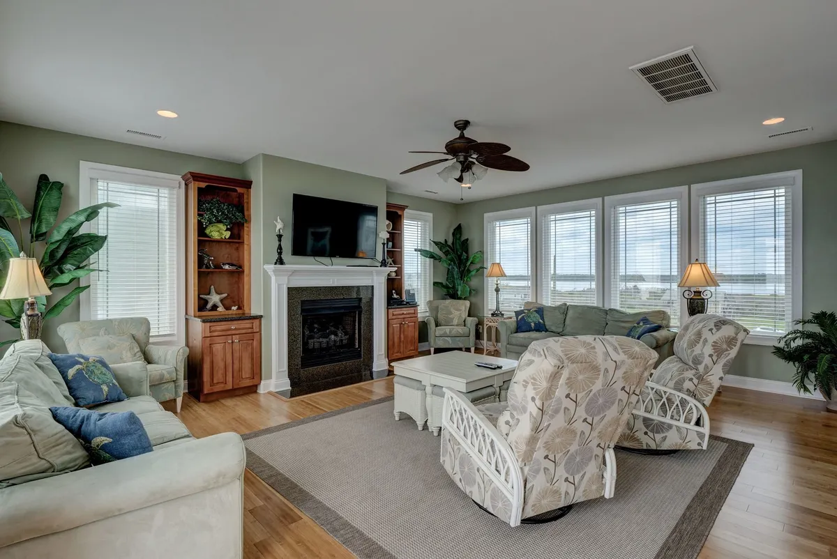 A cozy living area featuring comfortable seating, a coffee table, a fireplace, and large windows with scenic views. The space invites relaxation, socialization, and movie nights, echoing the narrative’s emphasis on togetherness and enjoyment of beautiful vistas.