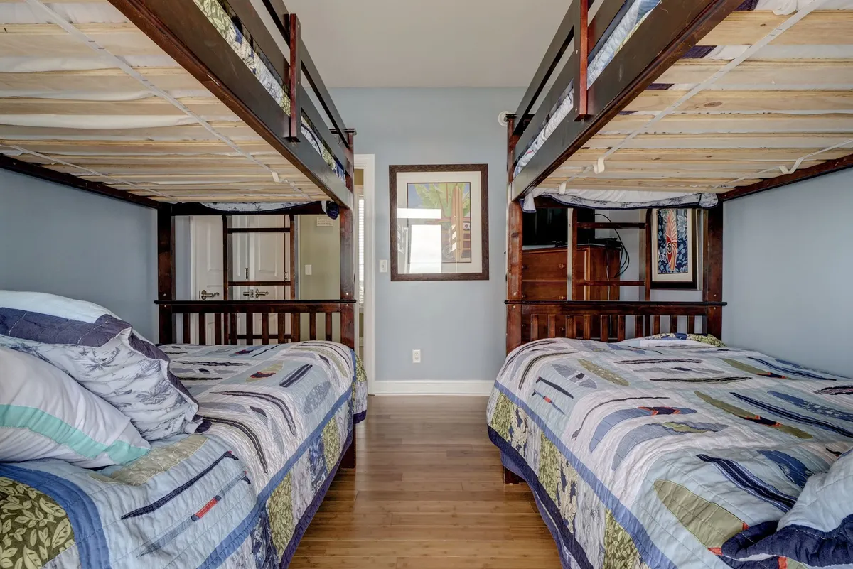 A cheerful bunk room with two bunk beds, each adorned with colorful quilts and playful artwork on the wall. The atmosphere is friendly and fun, creating a space where children can bond and share vacation memories.